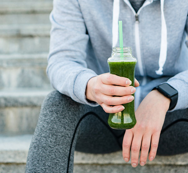 beverage_Formulation woman in workout attire holding healthy green drink